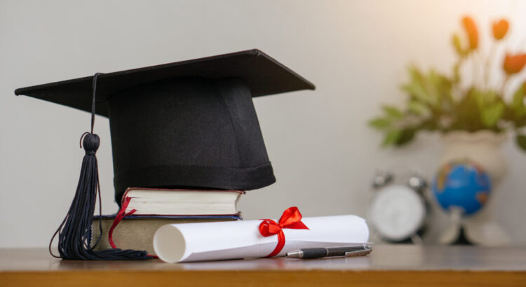 Mortar board with degree paper and books on wood table. graduati